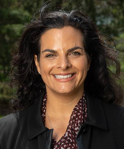 Photo of Dana Hebreard, a smiling white woman wearing a print blouse and a black jacket